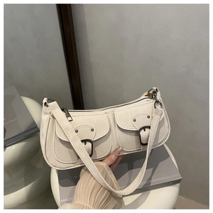 Detail of minimalist cream leather underarm bag featuring dual front buckle pockets