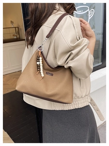 Détail du sac seau en toile marron avec breloque en perles de bois et lanières en cuir