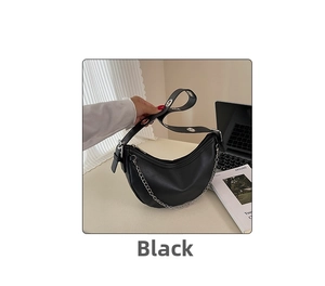 Detail of black leather crescent bag with chain and silver eyelet wide strap