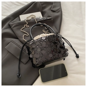 Detail of black sequined bucket bag featuring silver chain strap and cream drawstring liner