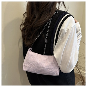 Close-up of lilac nylon shoulder bag with silver chain strap worn by a model
