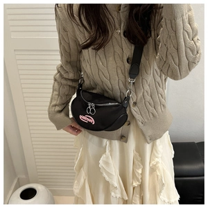 Dettaglio borsa a mezzaluna in nylon nero con ricamo FANYISSA rosa e zip in metallo