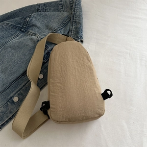 Marsupio minimalista in nylon beige abbinato a uno sfondo con giacca di jeans blu