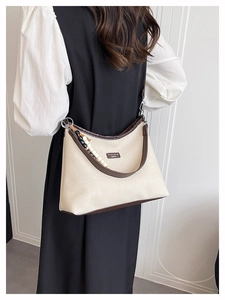 Détail du sac bandoulière en toile avec garniture en cuir brun et bijou de sac perlé