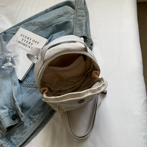 Cream nylon crossbody bag with spacious interior compartment and adjustable strap