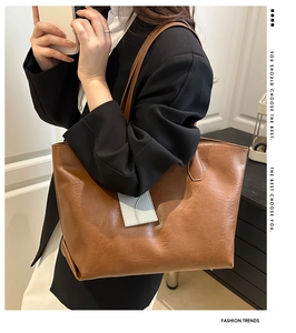 Detail of vintage brown leather tote bag paired with a black blazer for a commute look