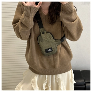 Detail of army green nylon mini chest bag with adjustable black strap on a model