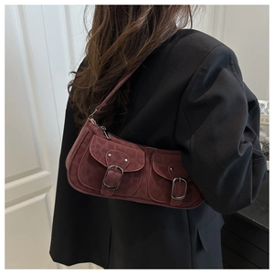Macro shot of dark burgundy suede shoulder bag with dual flap pockets and buckles