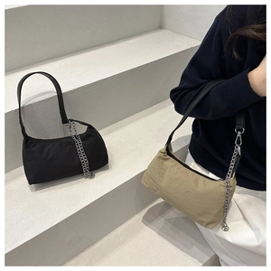 Detail of stylish nylon baguette bags in black and khaki with elegant silver chains
