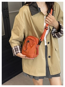 Detail of orange nylon crossbody bag featuring drawstring closure and brand embroidery
