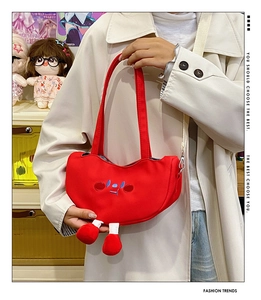 Detail of red canvas pea-shaped crossbody bag with cartoon embroidery and striped plush legs