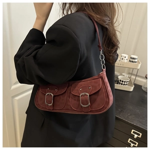 Detail of burgundy suede shoulder bag featuring two front pockets and silver metal buckles