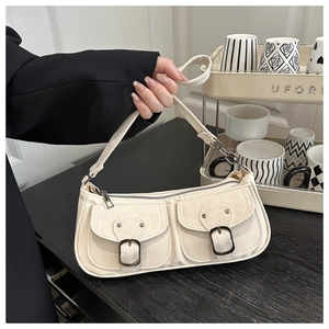 Détail du sac baguette blanc cassé avec deux poches avant vintage et boucles métalliques