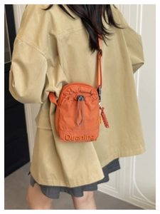Détail du sac à gourde orange avec fermeture à cordon et logo Duonling embossé sur tissu