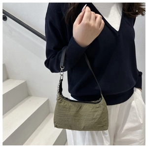 Detailed view of an olive green pleated nylon shoulder bag with silver chain accessory