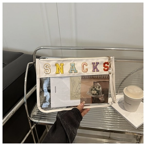Detail of transparent PVC and canvas bag with colorful embroidered SNACKS lettering
