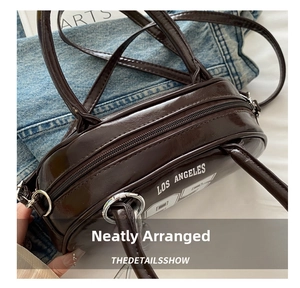 Detail of dark brown patent leather handbag with Los Angeles 95 print and silver zipper