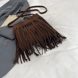 Sac bandoulière rétro en daim marron avec longues franges bohèmes sur fond de tissu blanc