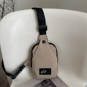 Minimalist khaki nylon chest bag with adjustable strap displayed on a white chair