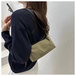 Olive green underarm bag with crinkle texture shown from a stylish side perspective