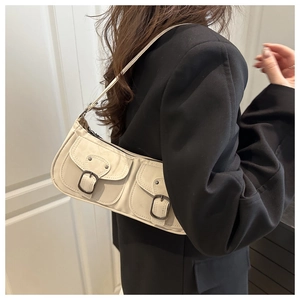 Détail du sac porté épaule ivoire avec deux poches à rabat et boucles métalliques