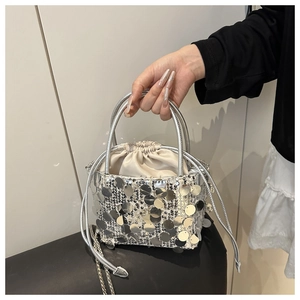Close-up of silver sequin bucket bag with drawstring closure and metal chain strap