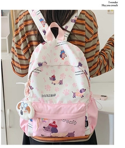 Close-up of pink cartoon backpack with puppy prints and plush dog head charm detail