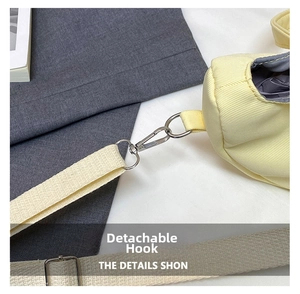 Detail of yellow shoulder bag featuring silver detachable metal hook and woven strap