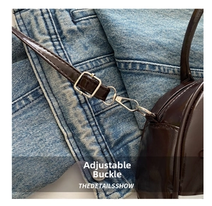 Detail of adjustable metal buckle and shiny brown leather strap on a tote bag