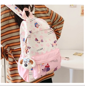 Close-up of pink canvas backpack featuring cute dog prints and a plush dog charm