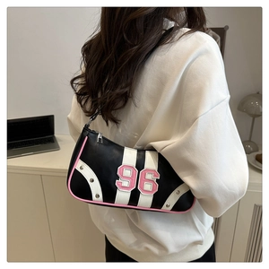 Detail of black leather shoulder bag with pink number 96 embroidery and metallic studs