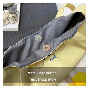 Detail view of the metal magnetic clasp and gray lining inside the yellow canvas bag