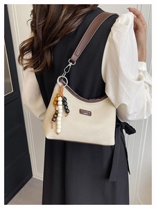 Detail of canvas bag with brown leather trim and retro wooden bead strap decoration