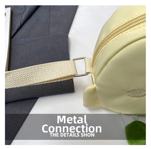 Detail of light yellow canvas bag showing silver metal buckle and woven shoulder strap
