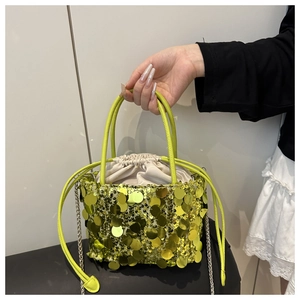 Detailed macro view of yellow sequin bucket bag with metal chain strap and drawstring