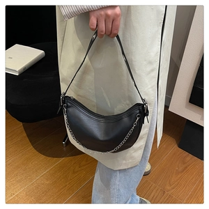 Detail of black crescent shoulder bag featuring silver chain and adjustable metal eyelets