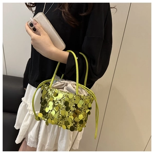 Detail of green sequin bucket bag with drawstring closure and metallic finish