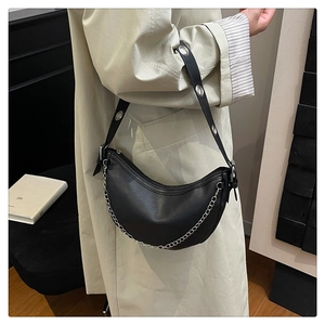 Detail of a black leather crescent shoulder bag featuring silver chain and wide grommet strap
