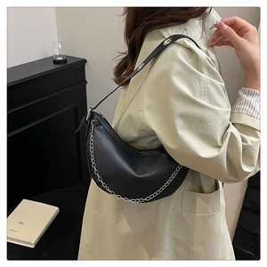 Detail of black soft leather hobo bag with silver chain strap and metal eyelet accents