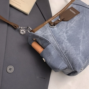 Elegante borsa a spalla in denim blu con finiture in pelle marrone e tasca laterale
