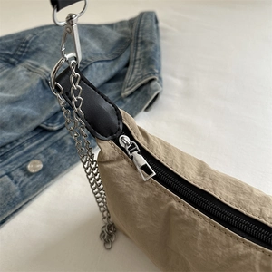 Khaki pleated crossbody bag with silver chain strap and zipper detail shown on denim