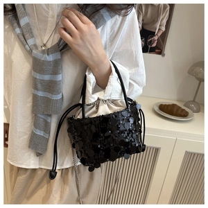 Detail of black sequined bucket bag with drawstring liner and elegant metal chain strap