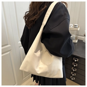 Close-up of minimalist cream white leather shoulder bag worn by model in a modern room