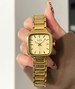 Détail d'une montre à quartz carrée dorée avec cadran champagne et date au poignet féminin