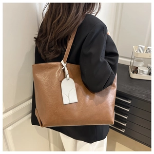 Brown leather tote bag featuring a decorative charm shown in a cozy indoor lifestyle setting