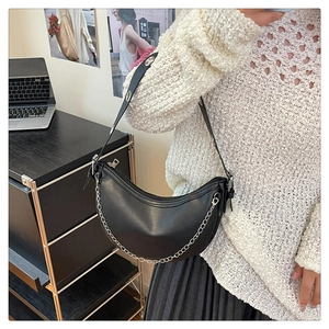 Detail of black crescent shoulder bag with silver chain and eyelet strap accents