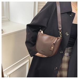 Detail of dark brown retro bucket bag with wide shoulder strap and gold hardware