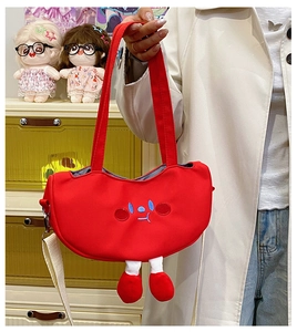 Detail of red canvas crossbody bag featuring a cute cartoon face and plush legs detail