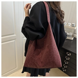Detail of burgundy animal texture on a large tote bag shown on model's shoulder