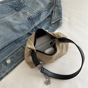 Khaki crescent dumpling bag with silver chain strap shown in a lifestyle flat lay view